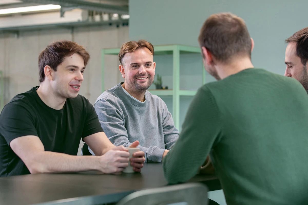 Das kubidat Team – Experten für IT-Consulting und Datenlösungen. Vier Personen sitzen an Mittagstisch und führen Gespräche in lockerer Runde.