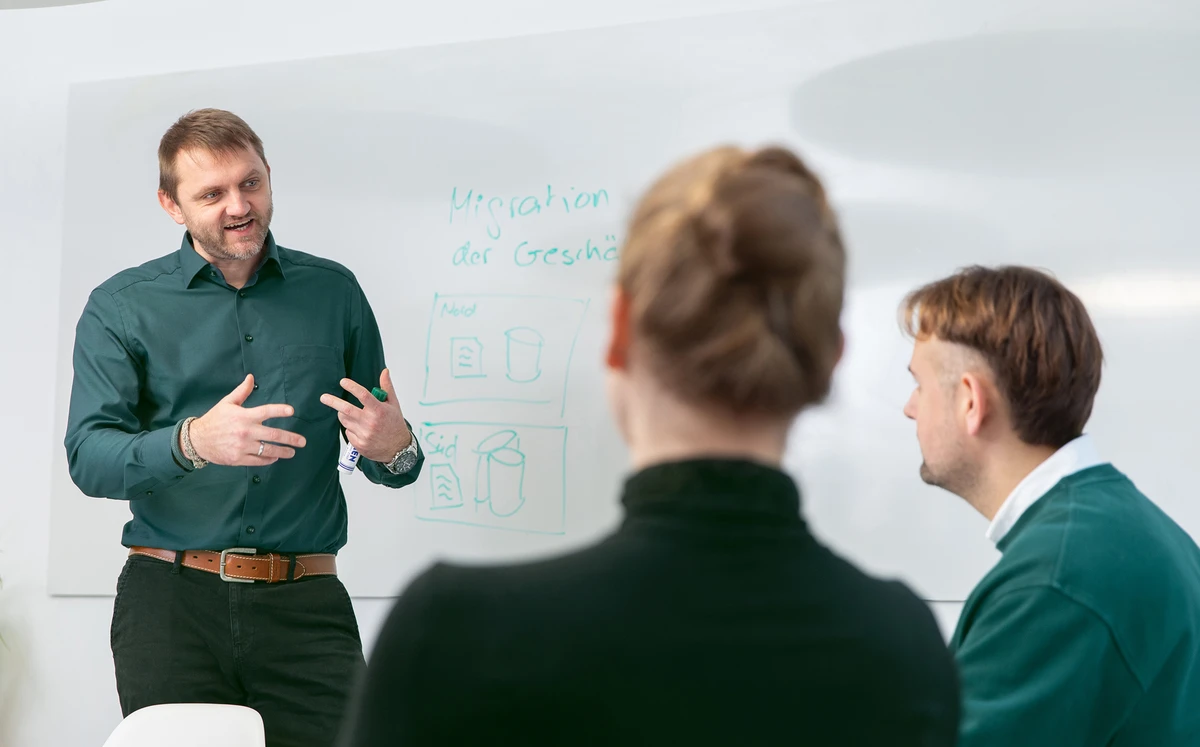 Person steht vor einem Whiteboard und erklärt Zeichnungen und Notizen.
