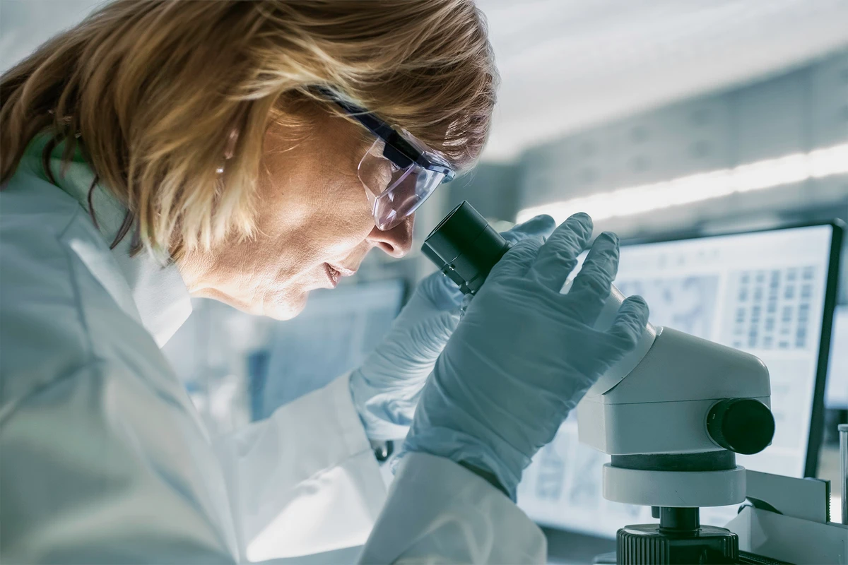 Wissenschaftlerin untersucht eine Probe mit einem Mikroskop in einem modernen Labor.